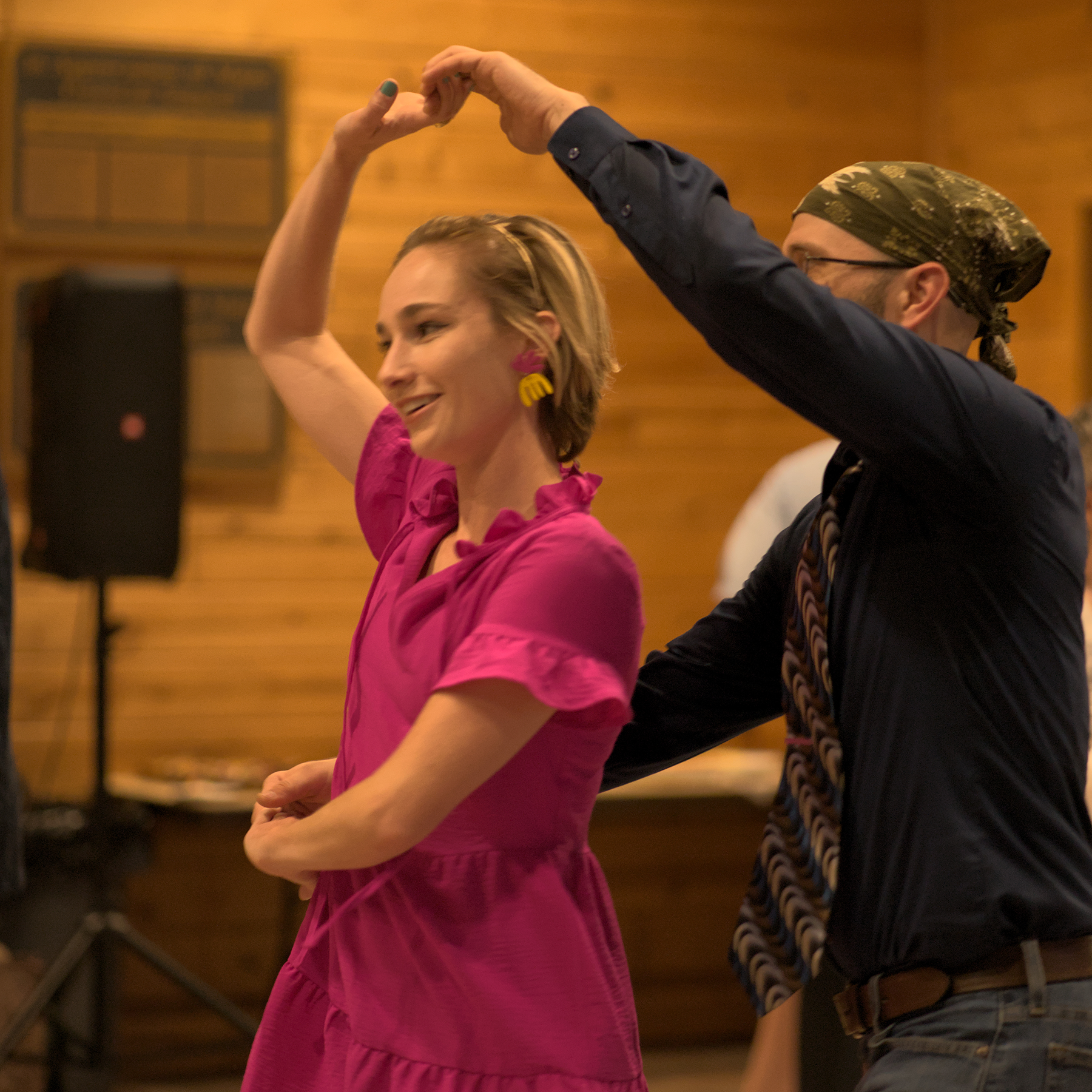 woman with short hair in a fucsia dress swing dancing with a man in a navy blue shirt