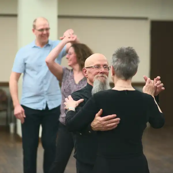 an elegant older couple dressed in black ballroom dancing