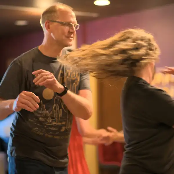 a couple dancing West Coast Swing, the woman's hair flying as she spins quickly